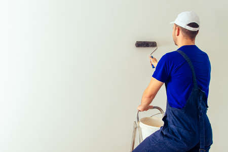 Painter man renovate apartment and coloring wall with paint rollerの写真素材
