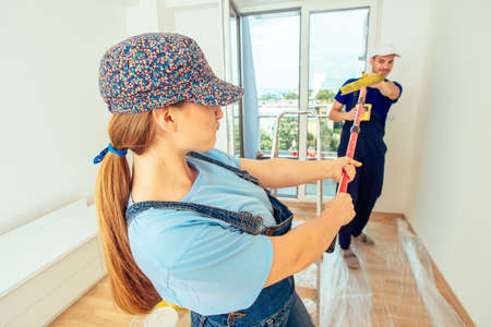 Young couple having fun while painting wall at home in yellow with paintbrush and paint stick rollerの写真素材