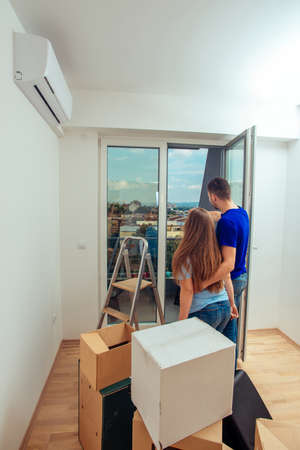 Husband and wife standing in their new living room with cardboard boxes