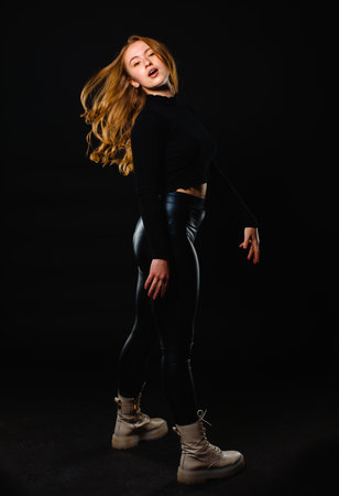 Young woman wearing leather black pants isolated on dark backgroundの写真素材