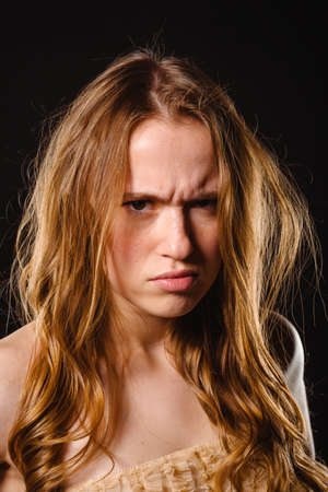 Portrait of an attractive trendy girl in beige top posing over black wallの写真素材