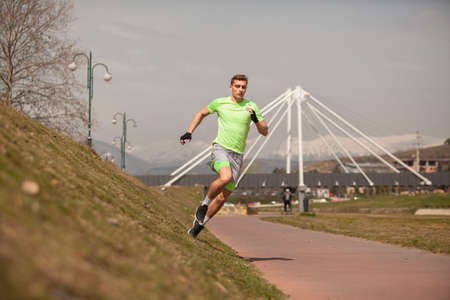 Handsome and attractive male sportsman is running on the side wall of the running trail