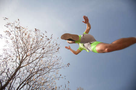 Handsome male sportsman is running and jumping above the camera, selective focusの写真素材
