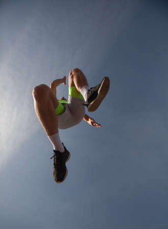 Handsome and attractive male sportsman is jumping above the camera, low angelの写真素材