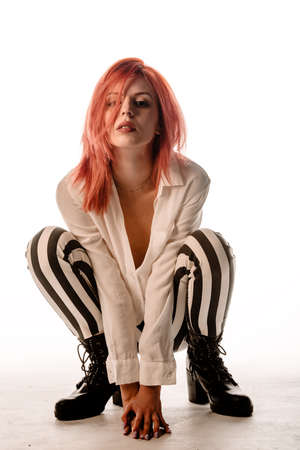 Body shot of a stylish woman posing in trendy pants and black boots against white background