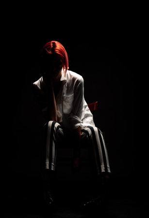 Stylish fashion girl posing while sitting on the cheir in modern studioの写真素材