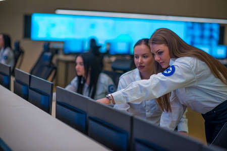 Security guard monitoring modern CCTV cameras in a surveillance room. Female security guards sitting...