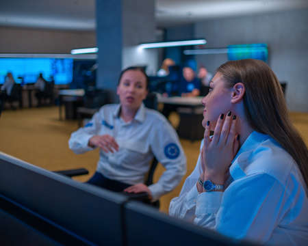 Close up photo of a security female agent monitoring the CCTV in a main data center office.