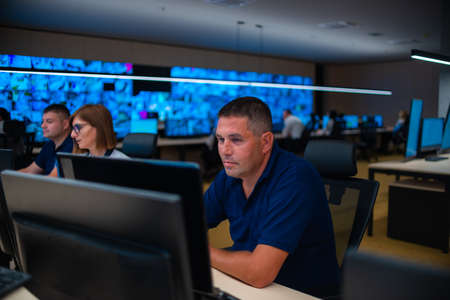 Group of Security data center operators (administrators) working in a group at a CCTV monitoring...