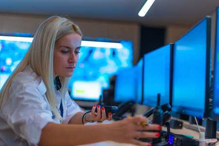 Happy security data center operator colleagues (coworkers) smiling and monitoring the CCTV footage while typing on a keyboard.の写真素材