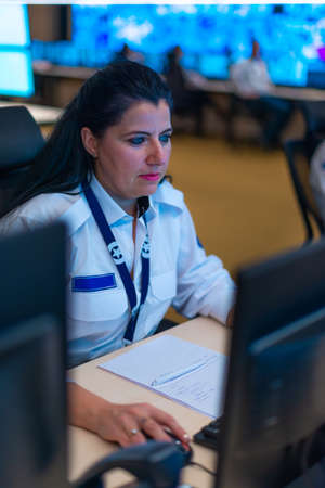 Happy security data center operator colleagues (coworkers) smiling and monitoring the CCTV footage...