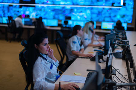 Group of Security data center operators (administrators) working in a group at a CCTV monitoring room while looking at multiple monitors ( computer screens)の写真素材