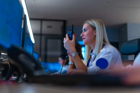 Happy security data center operator colleagues (coworkers) smiling and monitoring the CCTV footage while typing on a keyboard.の写真素材