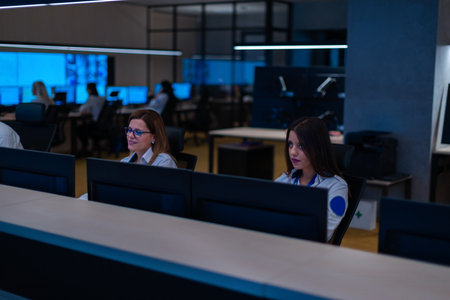Group of Security data center operators (administrators) working in a group at a CCTV monitoring...