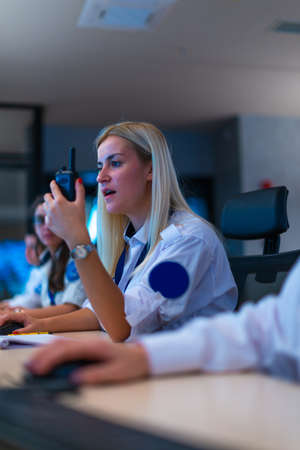 Happy security data center operator colleagues (coworkers) smiling and monitoring the CCTV footage while typing on a keyboard.の写真素材
