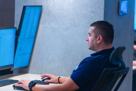 Side view of security system operator using walkie-talkie while looking at CCTV footageの写真素材