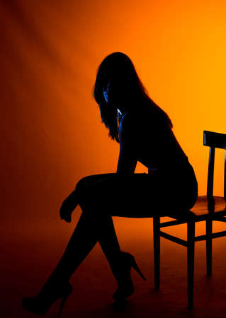 Body shot of a cool young woman wearing modern style black top sitting on cheirの写真素材