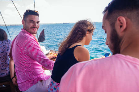 Three happy friends enjoying the sea view and the sunlight on a boat