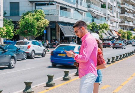 Stylish tourist calling a lift on his smartphone.
