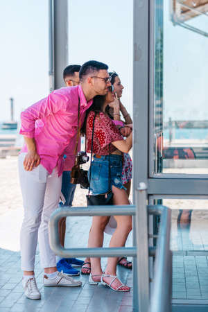 Young and happy tourists taking pictures with an old Polaroid in front of a modern building.の写真素材