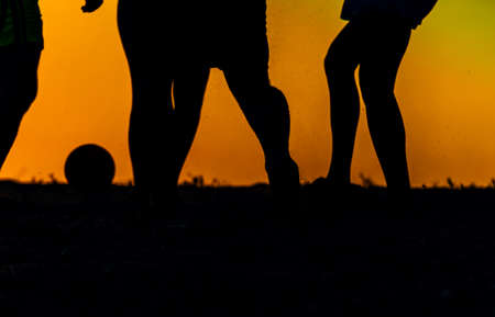 Silhouette people in nature playing football on sunsetの写真素材