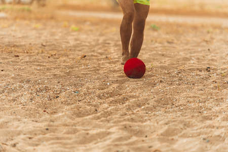 Caucasian man kicking soccer ball on sand beach at susnetの写真素材