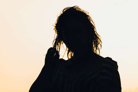 Silhouette of a beautiful sexual girl against the sea and sunsetの写真素材