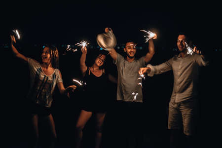 Couple holding a sparklers during nigh time on the mountain against evening sky