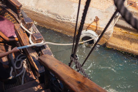 White rope securing wooden boat to city dock