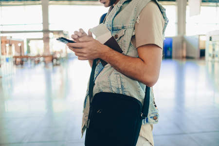 Portrait of a cool guy standing with mobile phone at airport stationの写真素材