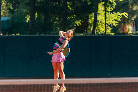 Professional equipped female tennis player serving the tennis ball on a sunny dayの写真素材