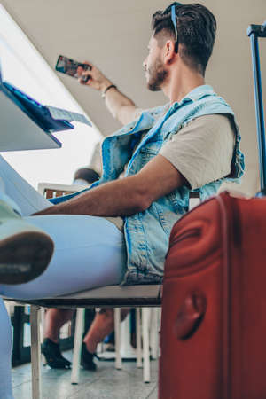 Close up portrait of a cool young guy taking selfie with mobile phone at airport