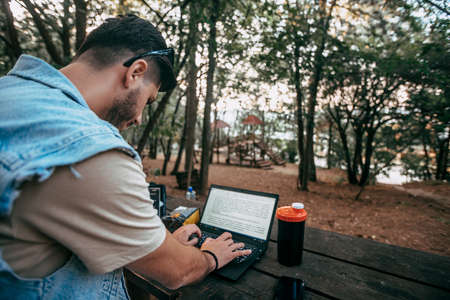 Confident man connected to wireless internet in nature, professional administrative manager checking online business report documentationの写真素材