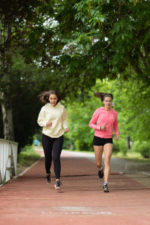 Two attractive girls are running together in the morning on their trackの写真素材