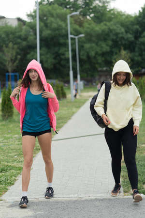 Two sweet and beautiful girls are going home after training because of the rainの写真素材