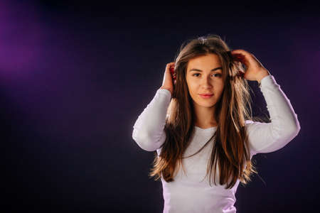 Portrait of an attractive girl holing her hair, while looking handsome and satisfied.