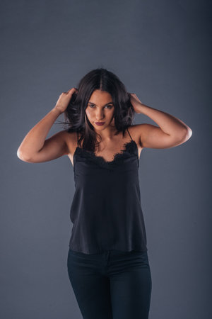 Portrait of a beautiful female model looking serious at the camera while touching her brunette hair