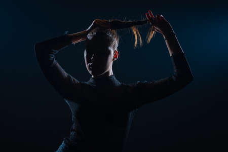 Dark contrast portrait of beautiful young woman with ponytail hairstyleの写真素材