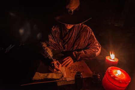 Young prophet Nostradamus writing his prophesies on a paper sitting in a ruined old church at nightの写真素材