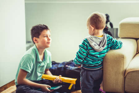 Two cute little brothers are sitting in the living room and playing togetherの写真素材