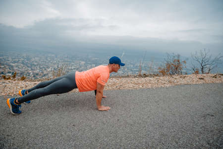 Athletic older man in sport clothes stretching his body before runningの写真素材