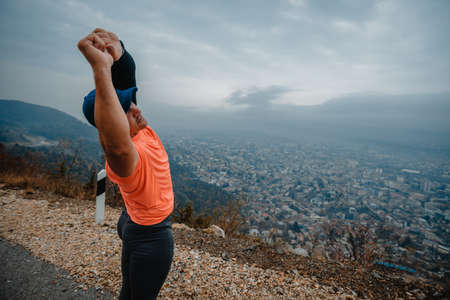 Muscular mature man over 40 in sportswear stretching outdoorsの写真素材