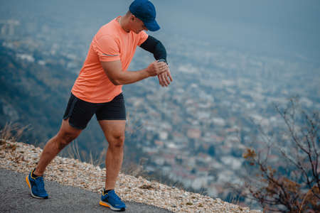 Older man in good shape checking his wrist watch during a run