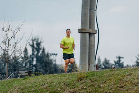 Older well built man in activewear running at a local park