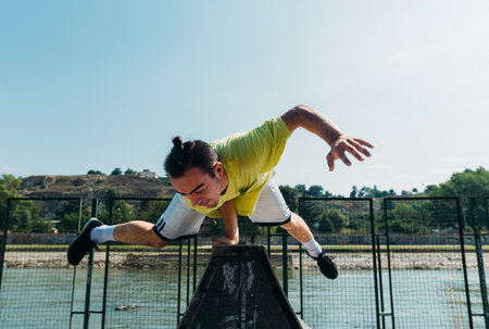 Sporty man maintains a balance on one hand in skatepark