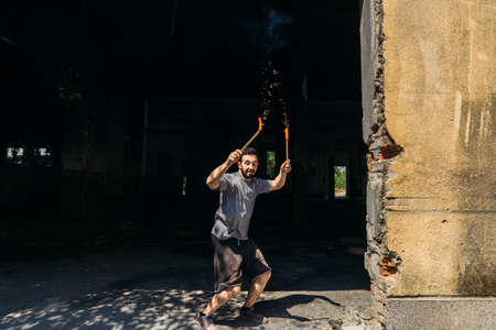 Cheerful guy with light sparklers in abandoned factoryの写真素材