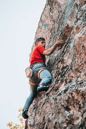 Man is engaged in sports rock-climbing. The climber climbs the rock. Outdoor activities