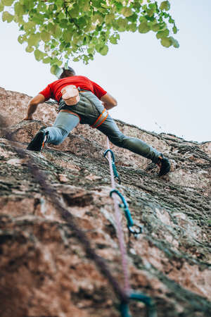Climber with climbing equipment hanging on a rope and falling down an rock-climbing wall