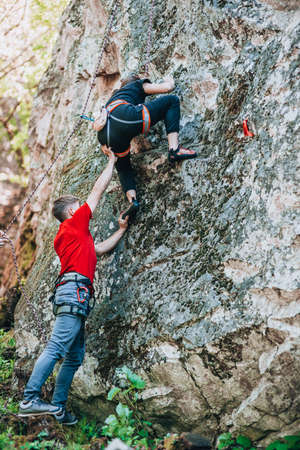 Climbing in nature. Friends train on natural terrain. A partner insures his friendの写真素材