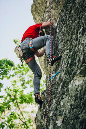 Man is engaged in sports rock-climbing. The climber climbs the rock. Outdoor activities